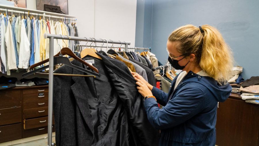 Program Manager in OSU’s College of Business Amy Newman looks through a selection of winter coats that hang from the racks of Benny’s Business Closet on Nov. 24, 2021. Benny’s is a business thrift store in Milam Hall on the Corvallis, Ore. Oregon State University campus that sells locally-donated business clothing to OSU students for a very affordable price.
