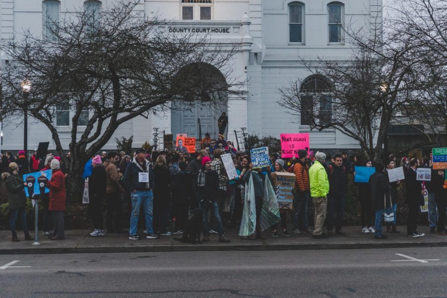 Protesters+gather+outside+around+the+courthouse+with+signs+as+cars+drive+by+and+honk+in+support.