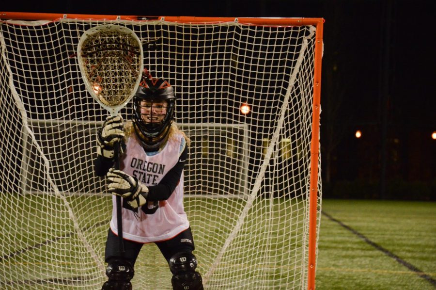 Noelle Hutchinson, the goalie for the Oregon State Womens Lacrosse Club Team, guarding the goal as the team begins practice at Student Legacy Park.