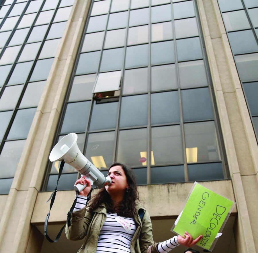 Solidarity March participant Marwah Al-Jilani speaking to march participants in front of Kerr Administration Building as a single office worker listens through the only open window. 