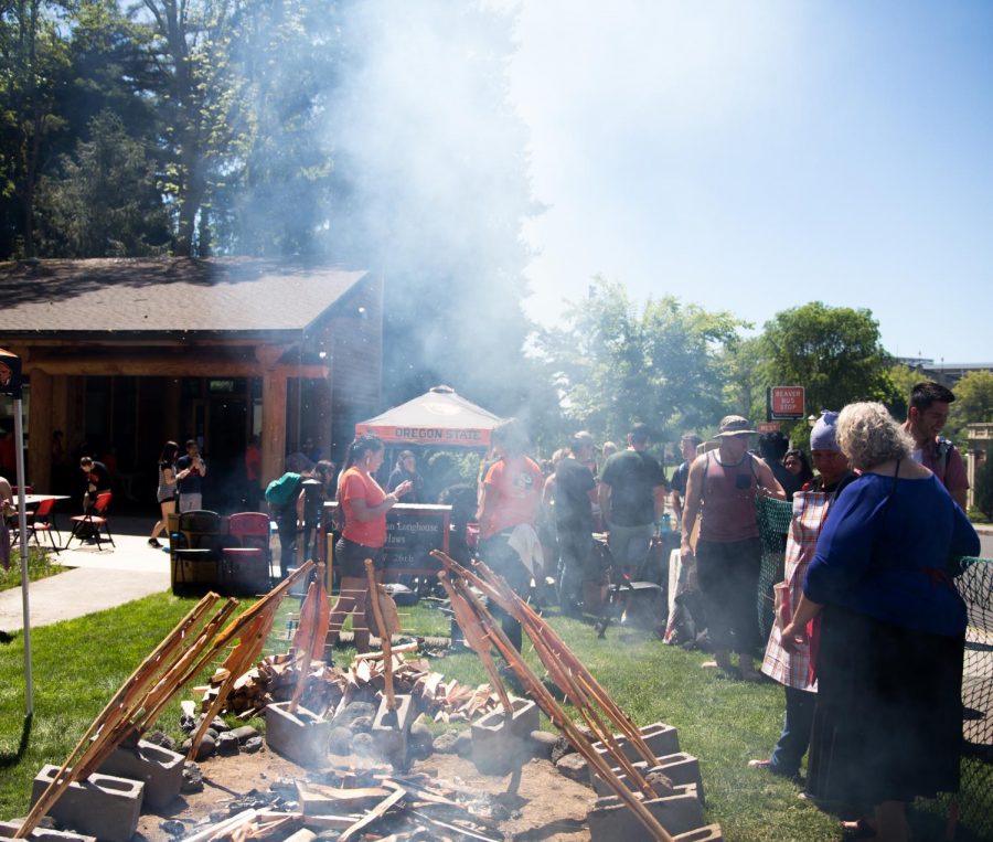 Attendees of the 19th Annual Salmon Bake gather around the fire where the salmon is prepared in the traditional way, served by the Longhouse on May 19. Those who waited in line were served salmon and multiple side dishes.  