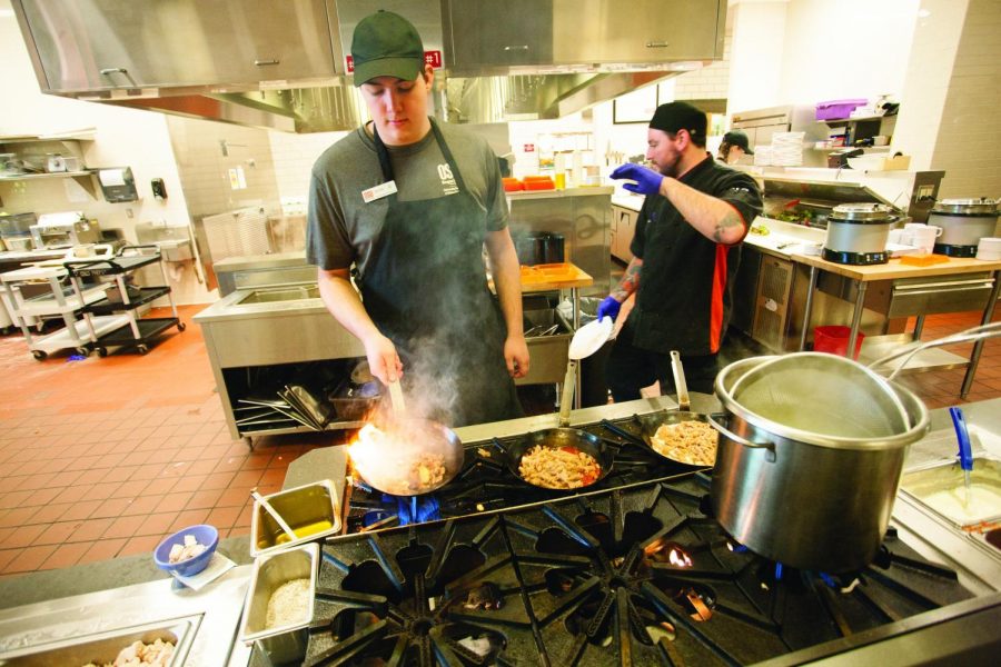 Devin Oar, a UHDS student employee, cooks a pasta dish while Dan Held, a full time Five Four One employee, protects himself from the steam.