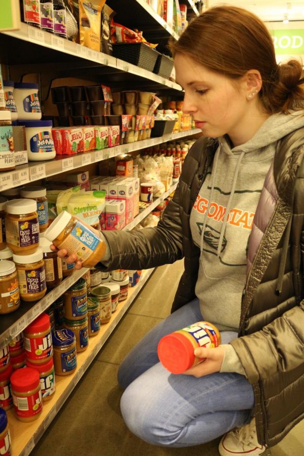 Bailey Reynolds, second-year biology major, compares peanut butter brands at Cascadia Market. Resources available to measure products’ impacts are located on the packaging.