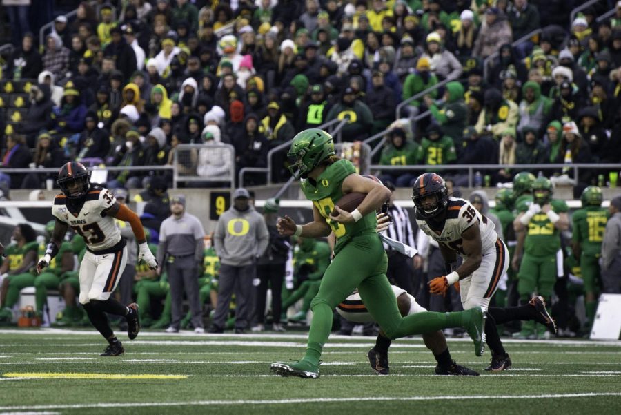 UO senior quarterback Justin Herbert escapes the pocket while OSU redshirt senior defensive back Jalen Moore (#33) and freshman inside linebacker Omar Speights (#36) follow the play. 