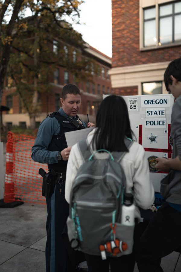Oregon State Police Trooper Daniel Ketcham speaks with Oregon State University students during a 2019 community fair in the Student Experience Center Plaza. 