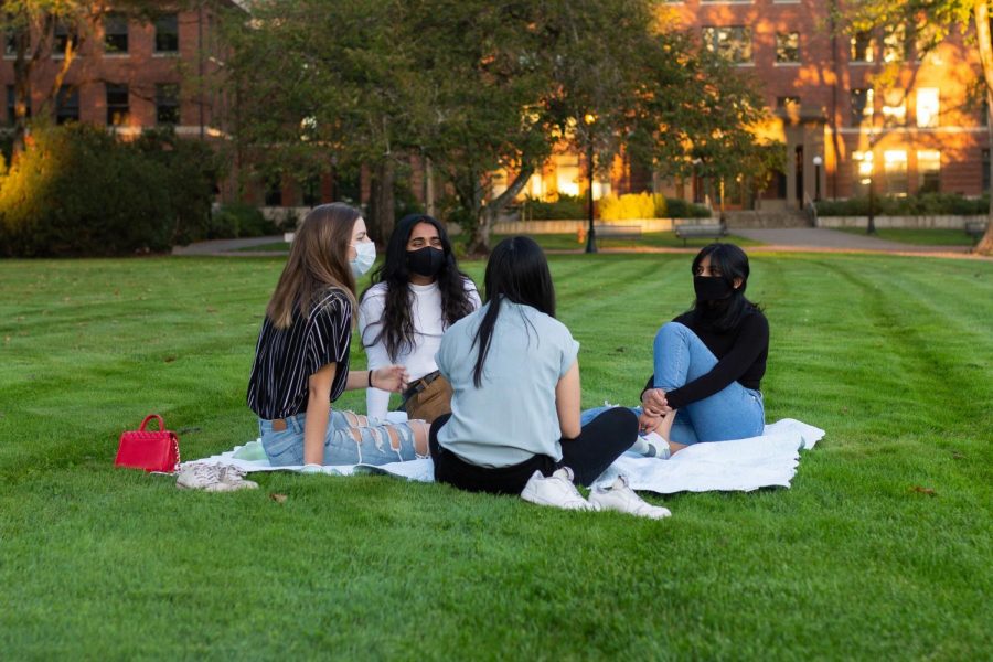 Juniors Julie Duong (back facing), Irene Walker (left), Aanchal Vidyarthi (middle), and Sowmya Jujjuri (right), spend their evening after classes lounging on the MU quad.