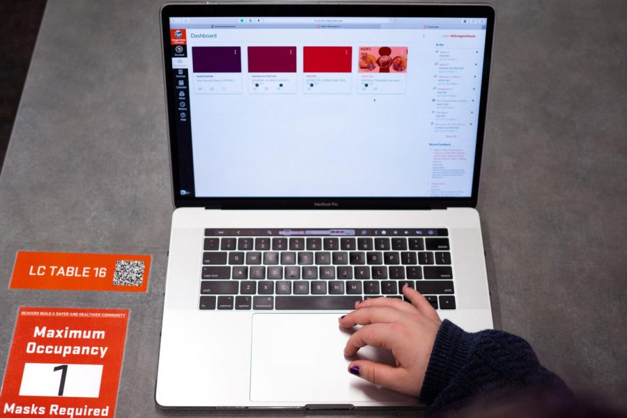 A laptop from the top view, A hand with painted fingernails is using the touchpad.