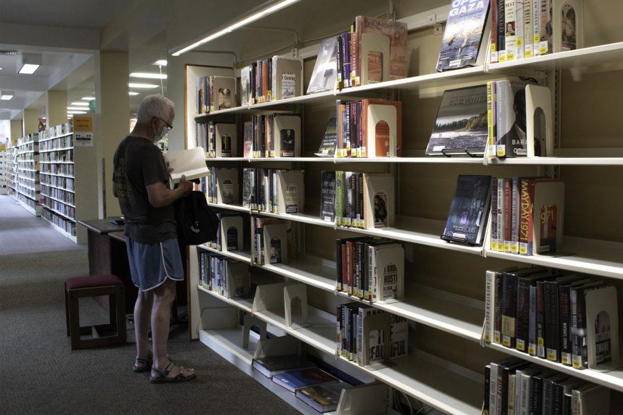 Scott Davis, a local Corvallis community member, browses through Corvallis-Benton County Public Library’s catalog of literature on Wednesday, July 28th. The CBCPL has now reopened to the public, and requires masks inside their buildings, except for patrons 5 and under.  