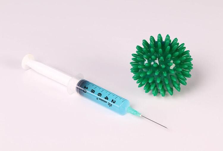 A photo illustration representing the COVID-19 vaccine and a representation of the COVID-19 virus’ structure. Unvaccinated staff and faculty now have to get weekly tests in hopes to minimize the spread of the virus. 