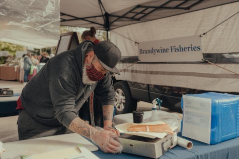 A vendor at the farmers’ market, Sam from Brandywine Fisheries, weighing salmon on Oct. 9. Salmon is integral to Indigenous cuisine in the Pacific Northwest.