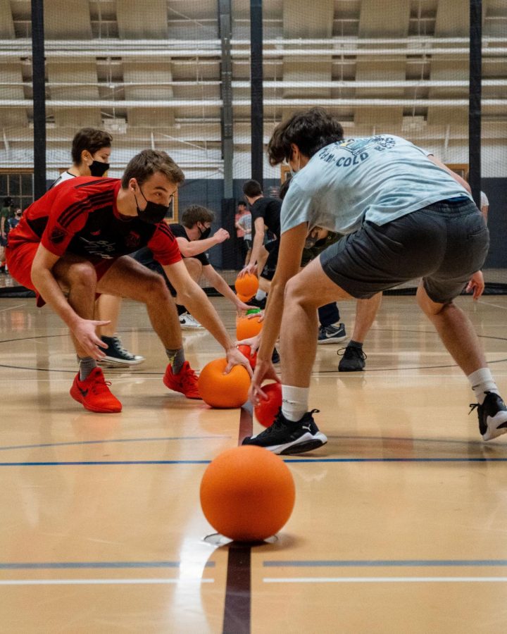 Two players from opposing teams race to grab a ball to start a game of dodgeball during the Dodgeball Club’s practice on Nov. 18. The Dodgeball Club has been meeting sporadically throughout the pandemic, able to have only 20 people on the courts over the past two years. 