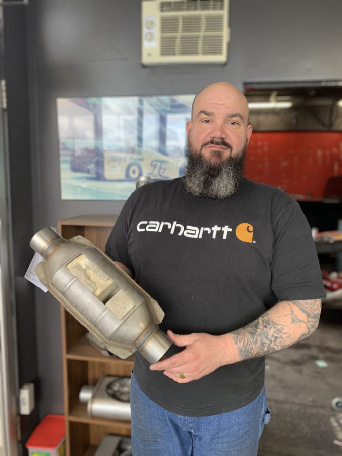 Owner of Jerrys Precision Muffler in Corvallis, Ore., Donald Jackson, holds a display catalytic converter in his shop. Jackson saw an increase in catalytic converter theft beginning in mid-2020. 