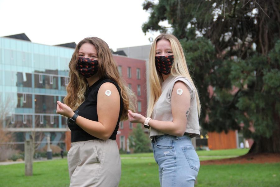Oregon State University first-year students Citlally Martin (left) and Love Fraijo-Meschelle display their bandages from receiving their COVID-19 booster shot. Omicron hospitalizations are expected to peak in Oregon this week while case counts remain high, and local health experts are continuing to advise vaccination.