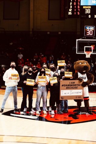 Pictured from left to right, Callan Jackman, Sierra Bishop, Emily Nagel, Caleb Etter, Jennifer Ruan, Christian Porter Lubbers, Sarah Connolly, Kristina Peterson and Benny the Beaver. These members of the Dam Worth It team pose with uplifting signs at the Jan. 20 OSU Men’s Basketball game vs. the University of Washington Huskies in Gill Coliseum.