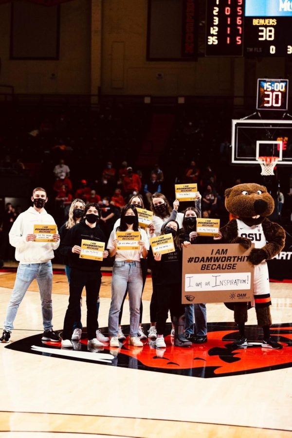 Pictured from left to right, Callan Jackman, Sierra Bishop, Emily Nagel, Caleb Etter, Jennifer Ruan, Christian Porter Lubbers, Sarah Connolly, Kristina Peterson and Benny the Beaver. These members of the Dam Worth It team pose with uplifting signs at the Jan. 20 OSU Men’s Basketball game vs. the University of Washington Huskies in Gill Coliseum.