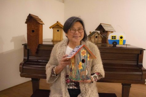 Executive Director of Corvallis’ Arts Center Cynthia Spencer-Hadlock (she/her) poses with wooden birdhouses on April 21 at the Corvallis Arts Center. These wooden birdhouses were donated by local woodworkers and will be put on sale at the 2023 Spring Garden Festival.