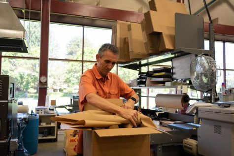 Joey McIntosh (he/him) packs paper in a cardboard box at OSU Printing and Mailing Services on May 15. OSU Printing and Mailing Services are responsible for printing and mailing ceremony programs, event passes for media and photographers, gift cards, and much more.