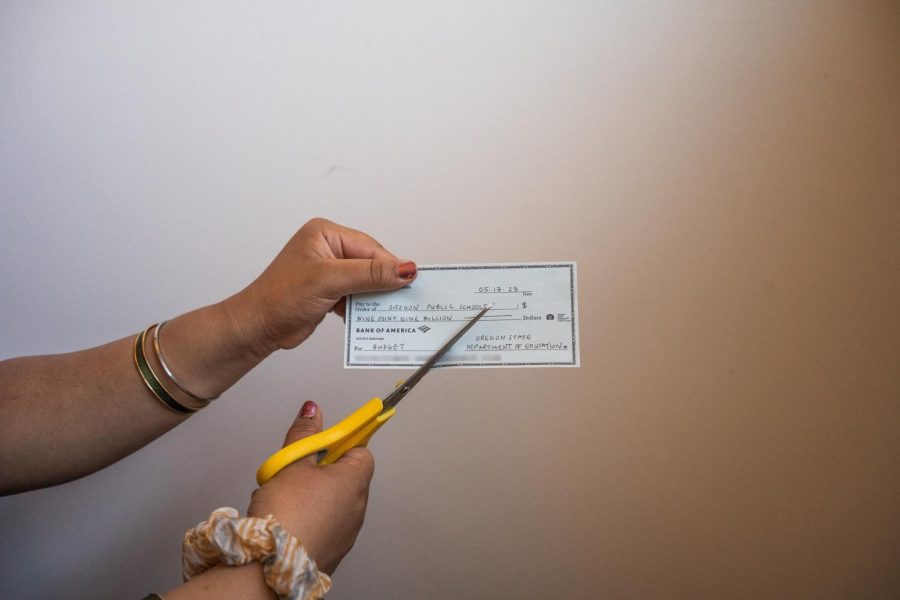 A photo illustration depicting a check being cut in half by scissors on May 17. The Oregon State Department of Education is giving Oregon Public Schools less funding than the needed amount.