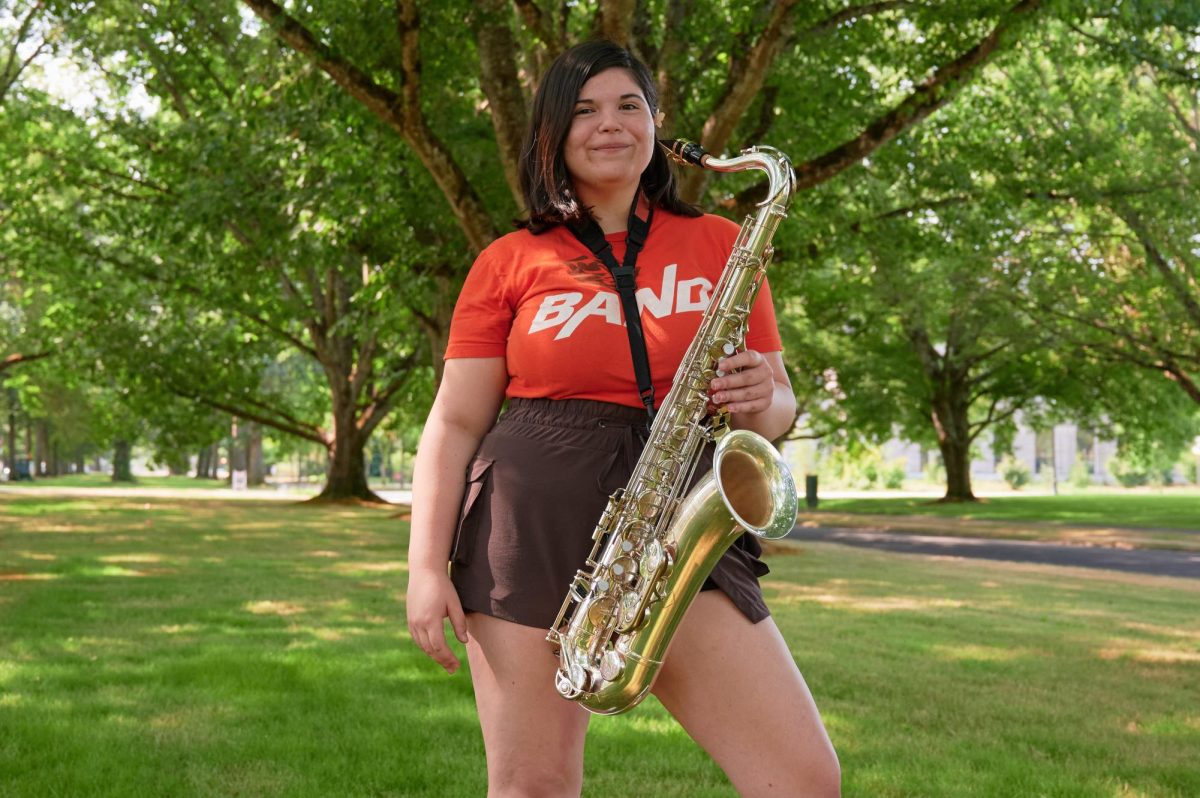 Fifth-year saxophonist Mayri Ross (she/they) poses with her saxophone on OSU campus on August 16. Ross shows excitement with her instrument as she is passionate about Marching Band.