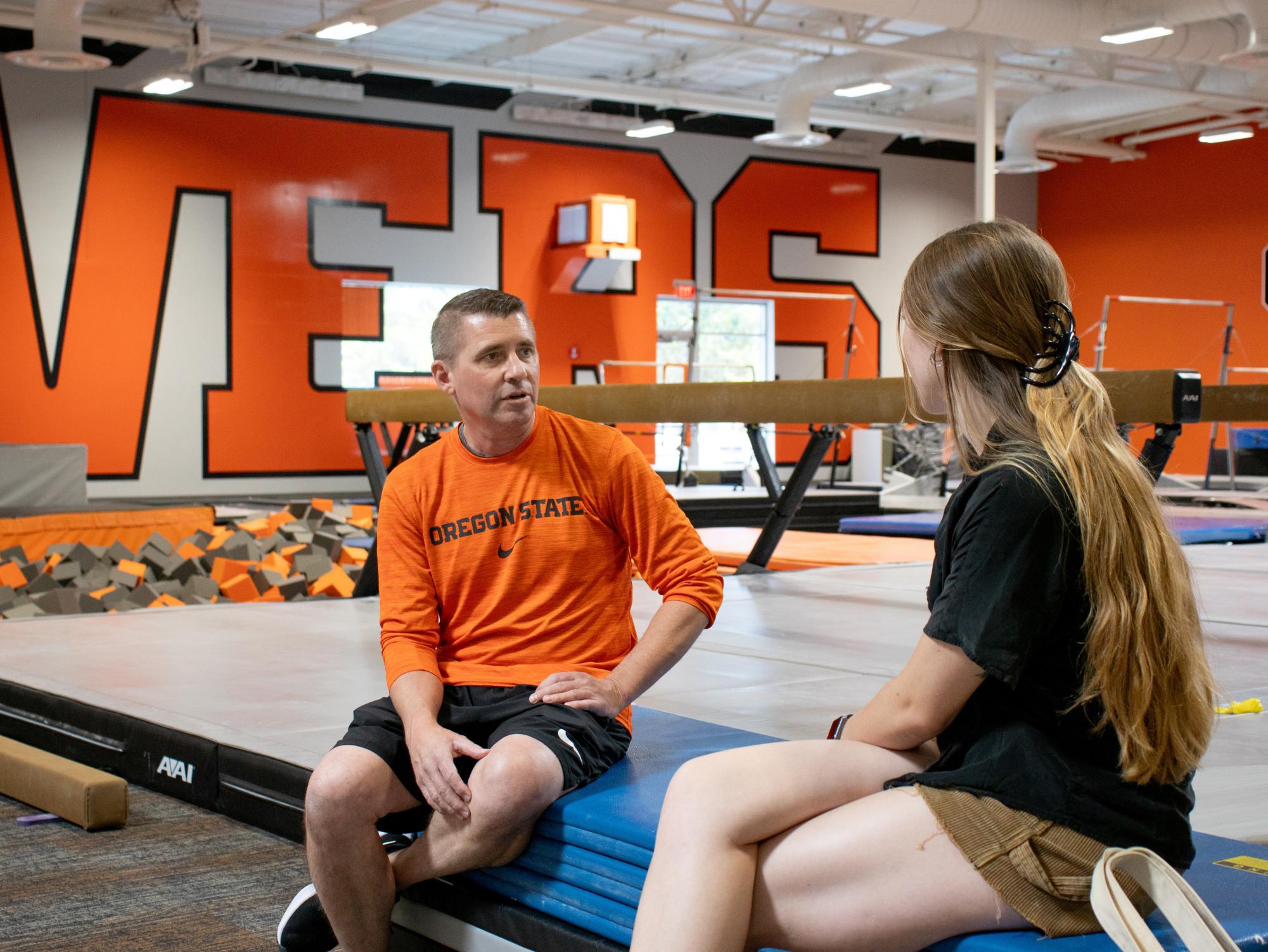 Oregon State gymnastics coach Brian Carey (left) speaks with third-year Kinesiology major Riley LeCocq (right) about his plans for the season in the Gymnastics Practice Facility on August 11 2023. Carey, recently hired, is the father of third-year gymnast Jade Carey and has coached for Team USA.