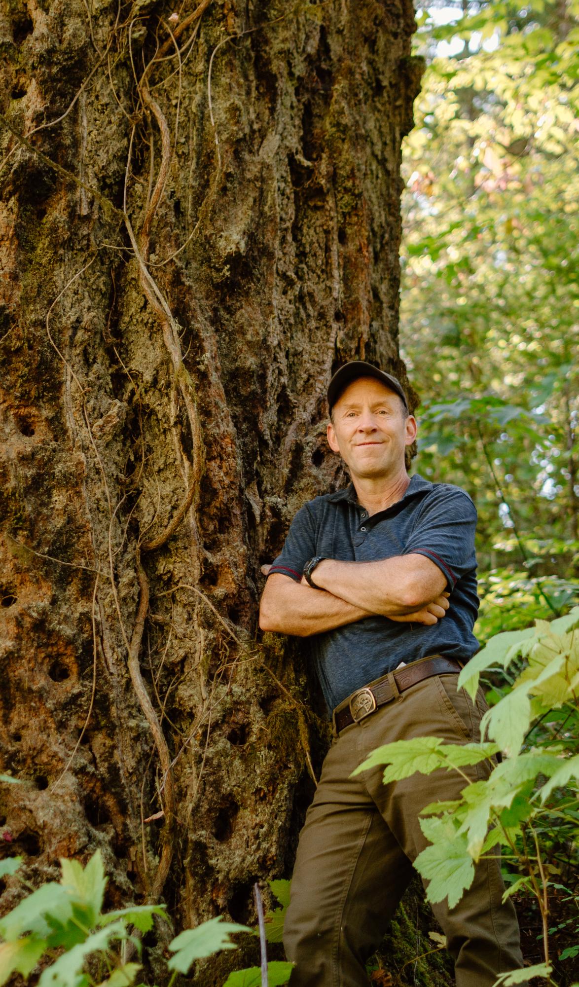 Doug Pollock standing in front of old-growth tree. 