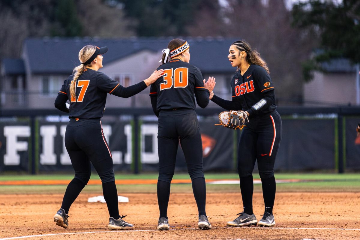 Grace Messmer (17), Sarah Haendiges (30), Lici Campbell (24) meet in the infield at Kelly Field on March 9 in Corvallis, Oregon.