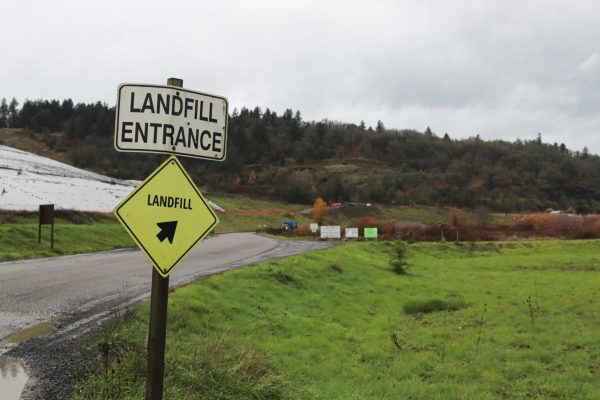 Sign notifying the Landfill entrance with the landfill itself behind it
