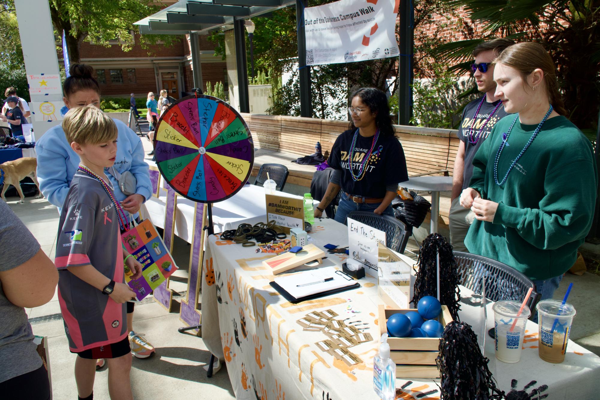 Dam Worth It members Aria Wallace, Jackson Harding and Sophia Fischer talk with community members in attendance at the 2024 Out of the Darkness Walk held on Oregon State University’s Corvallis campus on April 20.