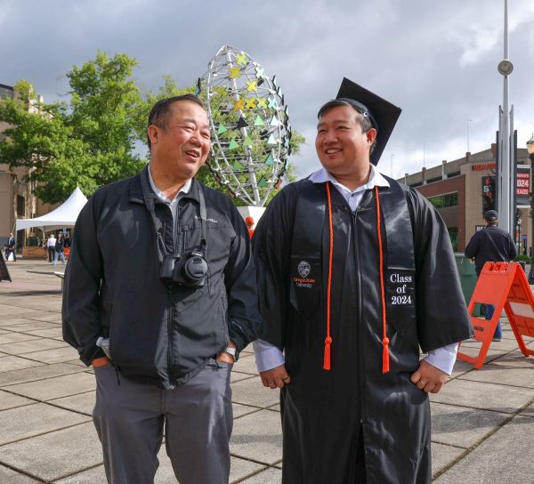 Dac Nguyen (left) describes his son (right) graduating from OSU at Oregon State University’s Reser Stadium in Corvallis, OR, on June 15th, 2024, before the 155th graduation commencement ceremony. 