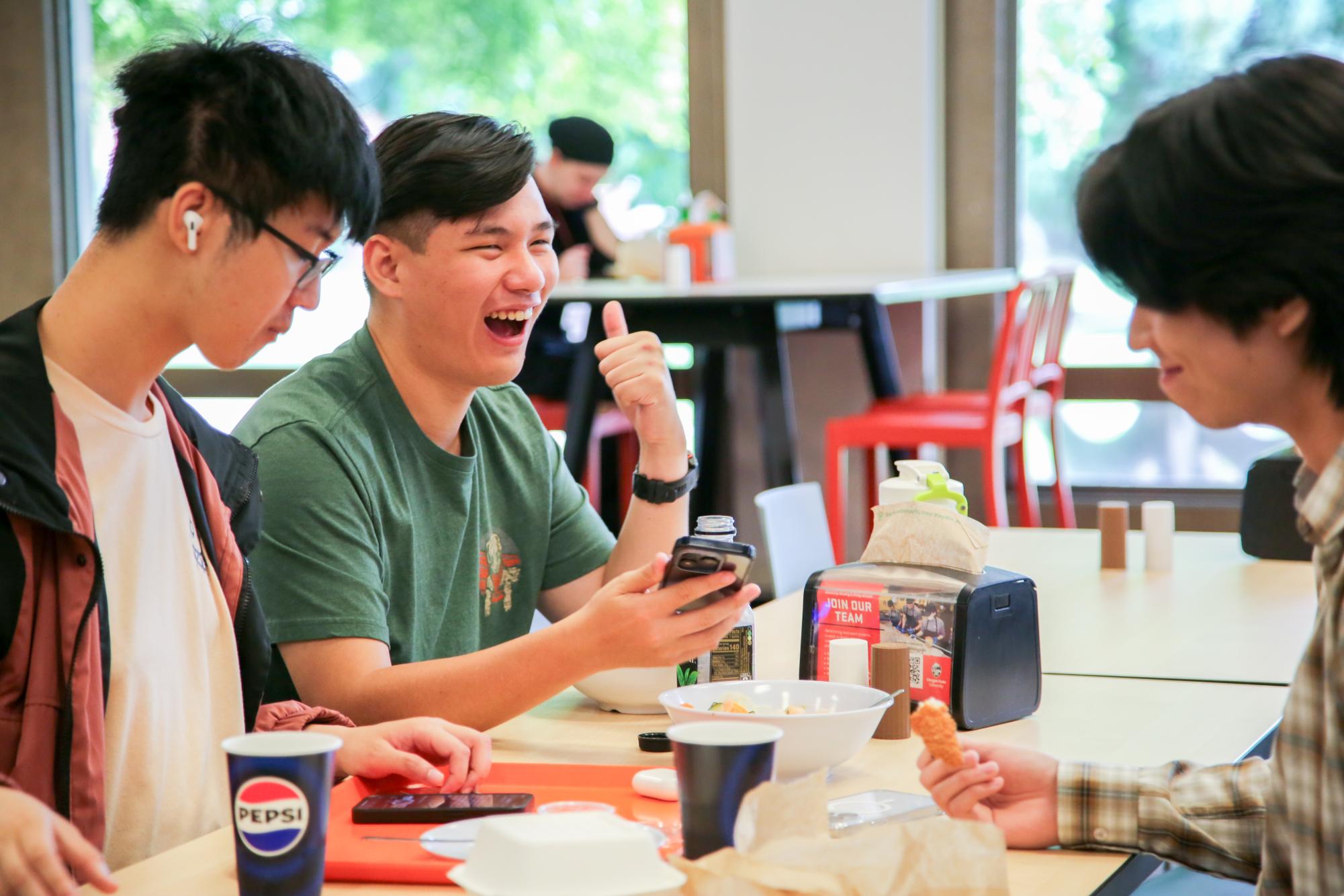 Students, Kanta Moriyasu, Che-Yu Chan, and Chang-Ming Lin eat lunch and laugh at Oregon State University’s Arnold Dining Hall on August 15. 