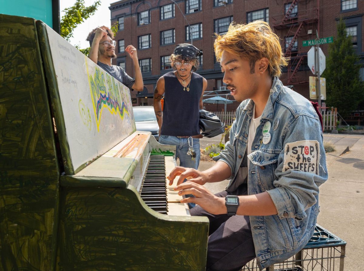 Dylan de Honor sings and plays the piano with their friends Celio and Jordan on the corner of Madison Avenue and 2nd Street in Corvallis during the Saturday Market on September 7, 2024. 