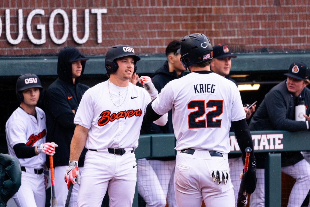 Jacob Krieg (22) fist bumps with his teammate after running through home base at Goss Stadium, Coleman Field in Corvallis Oregon on April 5.
