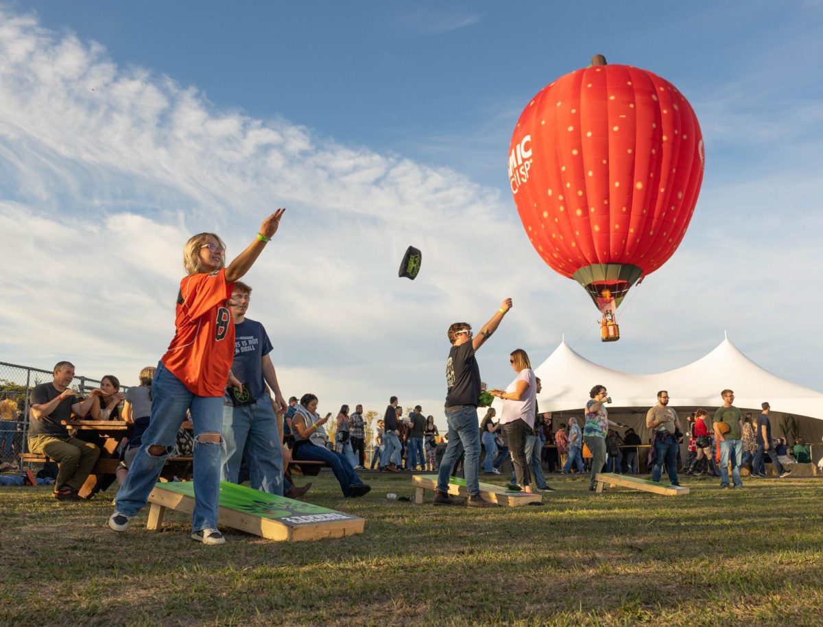 Thea Herrick, an OSU student studying Mechanical engineering, tosses a bean bag in a game of cornhole in front of the “Cosmic Crisp” hot air balloon during the 2 Towns Ciderhouse 14th annual Harvest Party on Oct 19 in Corvallis, OR.