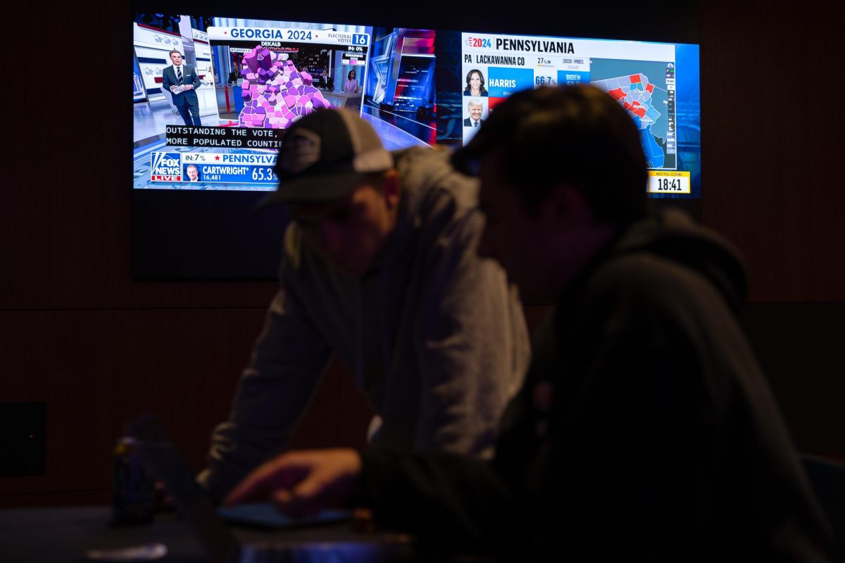 Electrical engineering student Gabe Ryley (left) and psychology student Jonah Davison view incoming 2024 election results on their devices at the Memorial Union Election Night Coverage event on Nov. 5.