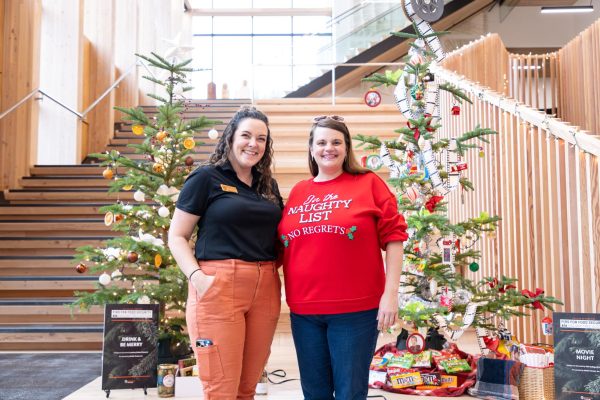 Co-chairs of Rootstock Madison Dudley (left) and Jessica Fitzmorris stand in front of two "Firs for Food Security" auction tress at the College of Forestry Holiday Craft and Art Fair in Peavy Hall on Dec. 6, 2024.