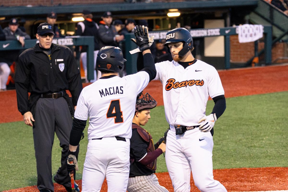 Dallas Macias (4) high fives teammate Jacob Krieg (22) after scoring two points at Goss Stadium, Coleman Field in Corvallis Oregon on April 5.