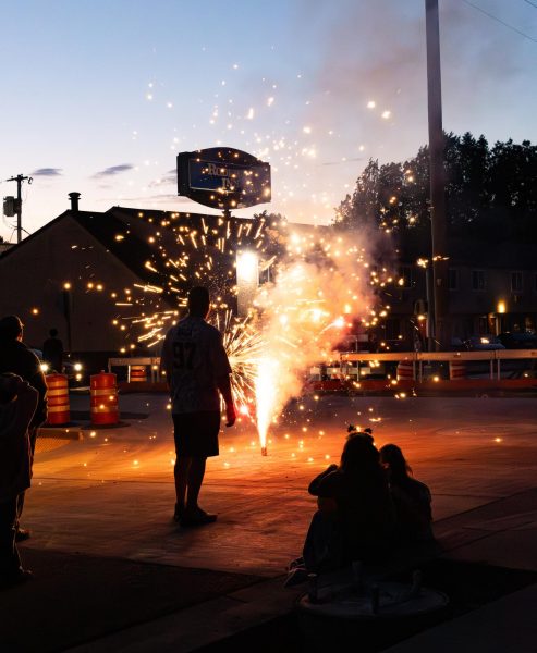 Man looks at firework shooting from the ground.