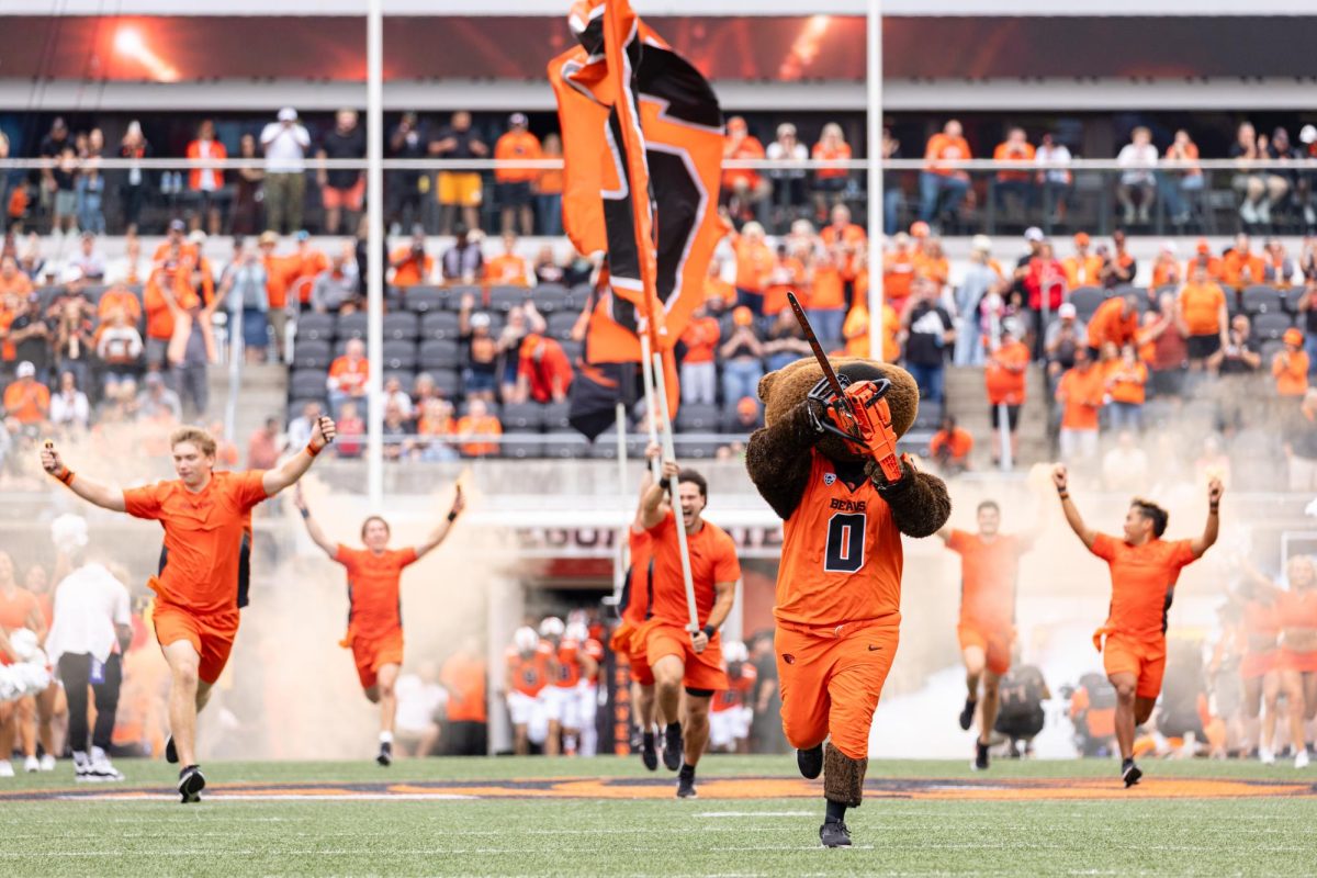 Benny the Beaver leads the Oregon State University cheer team, followed by the football team to enter the stadium at the game against Fresno State University on Sept. 6, at Reser Stadium.
