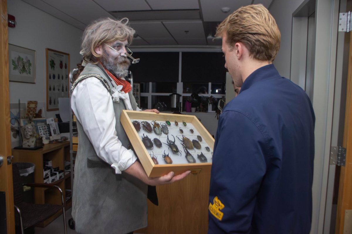 Chris Marshall, curator of the arthropod collection, shows students beetle specimens in a display case while in costume during Night at the Museum on Oct. 23. These specimens and other collections were on display in a walk through of Cordley and Nash halls to excite students about science.