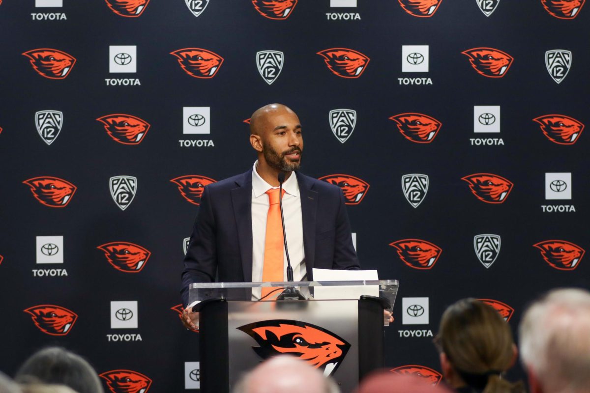 A man in a suit stands at a podium in front of a backdrop.