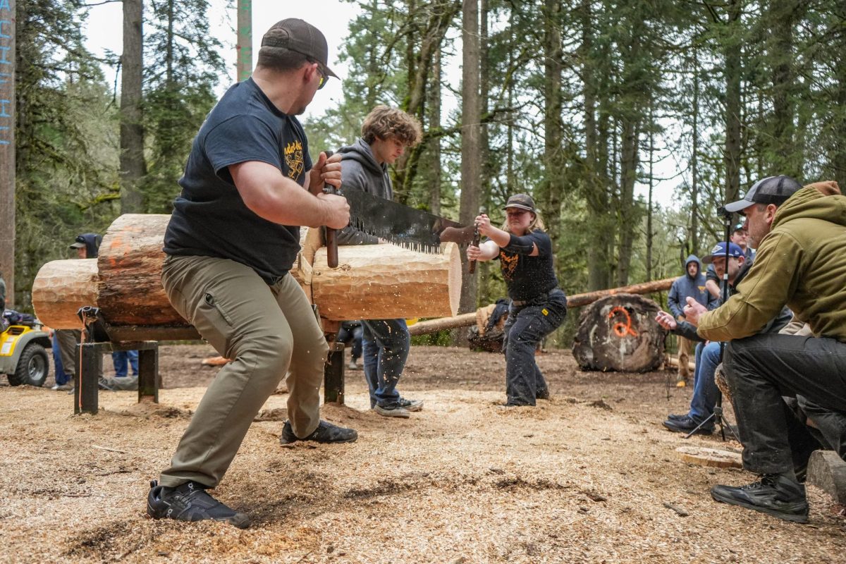 Teammates from the University of Idaho “Vandaljacks” logging team share a saw for theJack and Jill event
