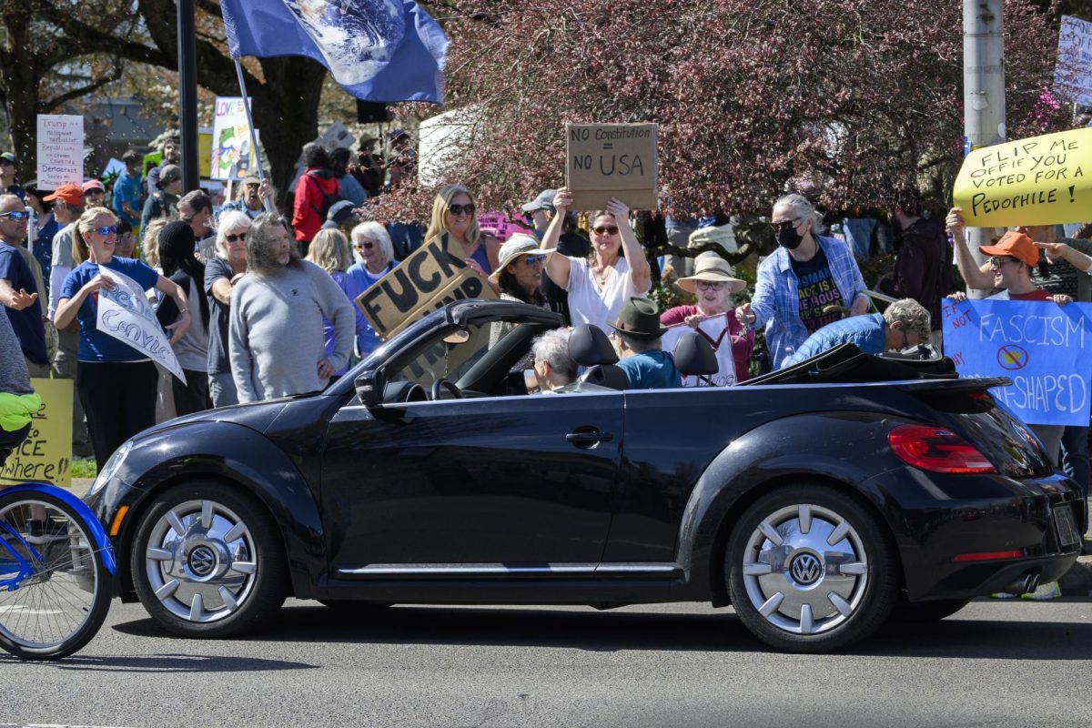 A driver and passenger in a convertible interact with protestors in front of the Benton County Circuit Court