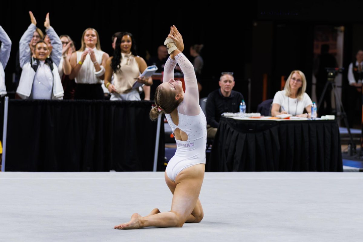 A gymnast strikes a pose on her knees during her floor event.