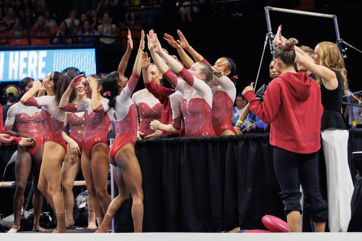 University of Alabama gymnasts celebrate and high five each other.