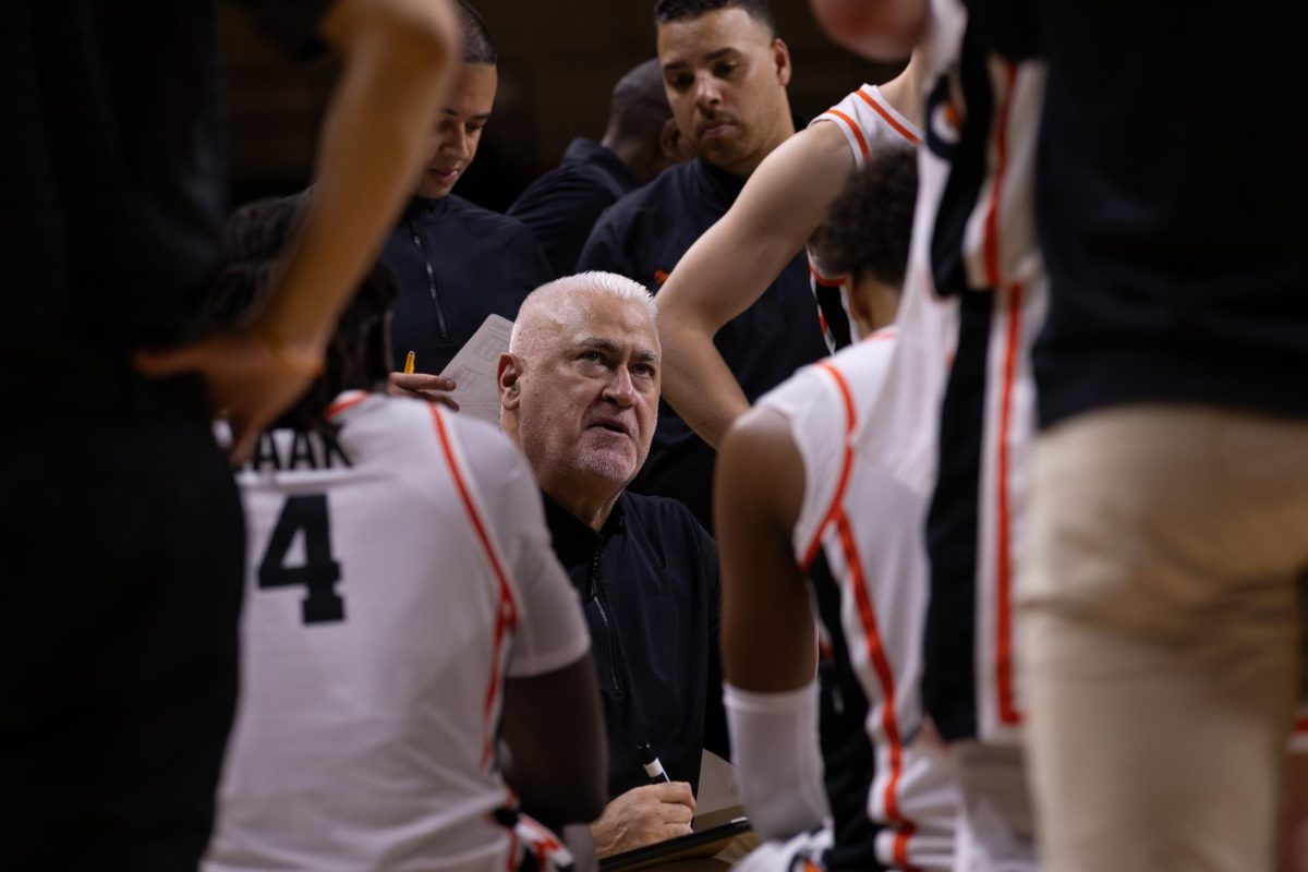 Basketball players surround the head coach on the bench during a basketball game.