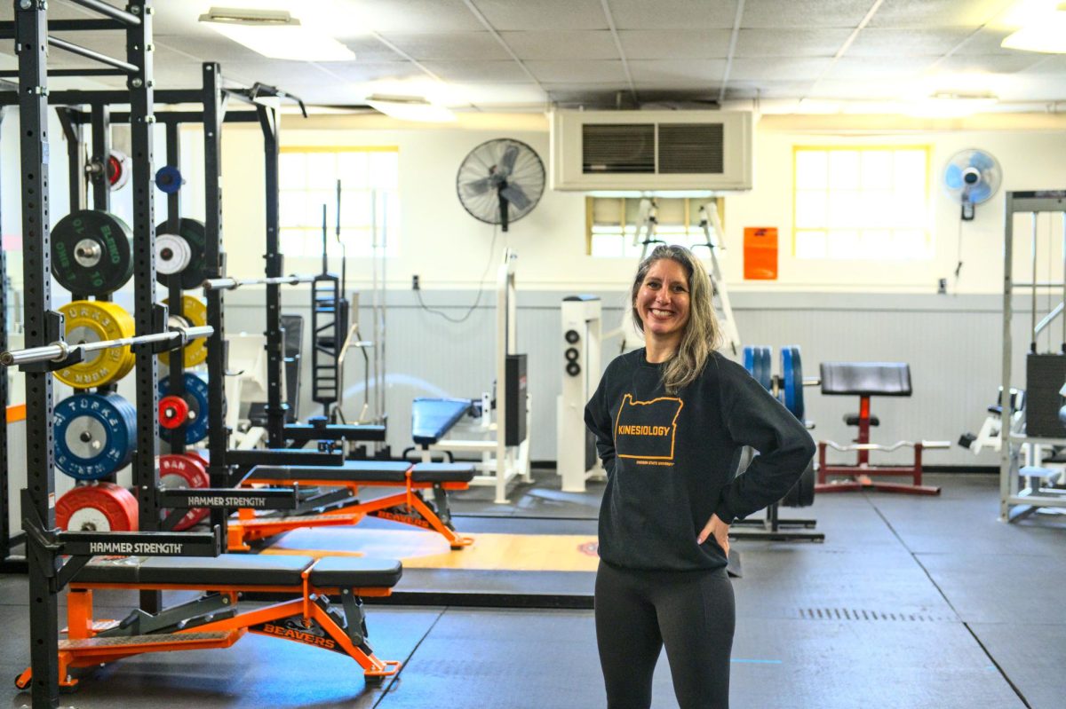 A woman stands in a room with weight training equipment.