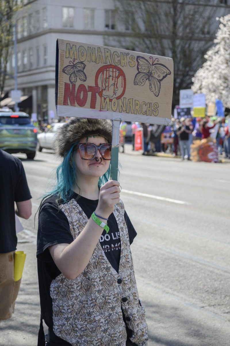 A woman stands on the street holding her protest sign.