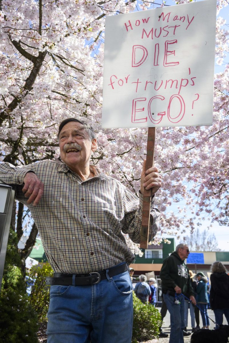 A man leans against a post holding his protest sign.