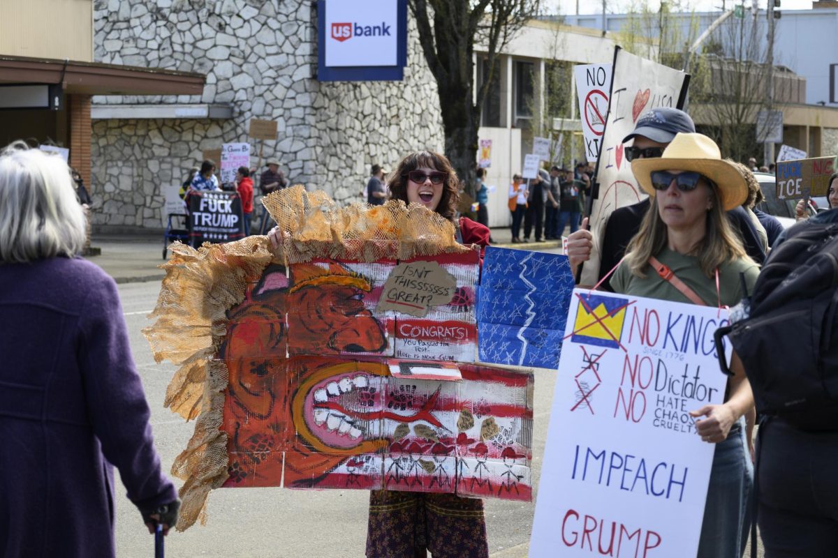 A woman stands on the street holding her protest art.