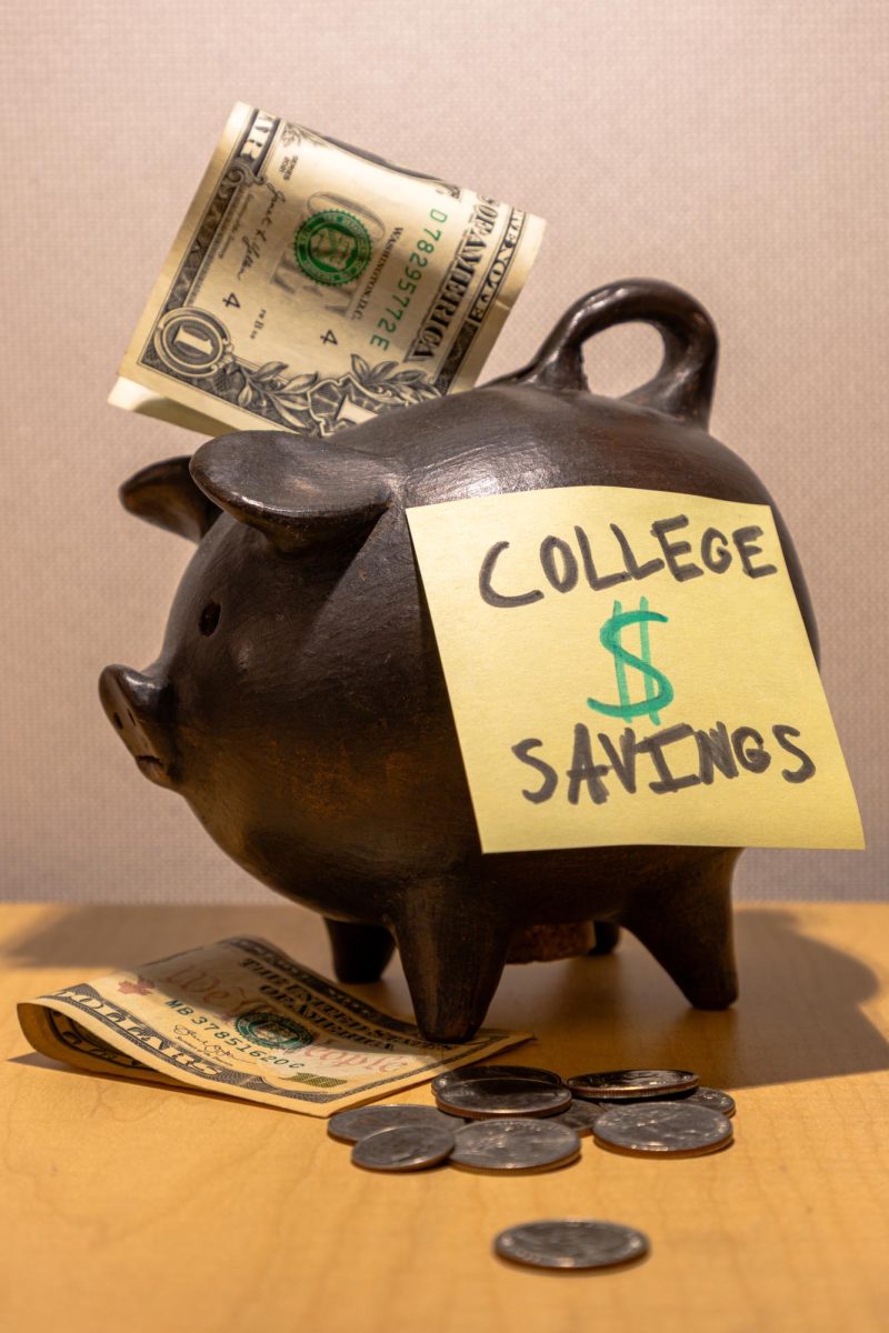 A piggy bank with money around it and a sticky note on it that says college savings.